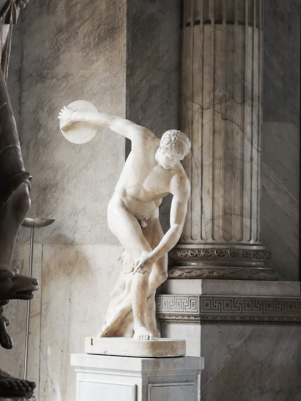 Marble statue of a discus thrower beside a fluted column