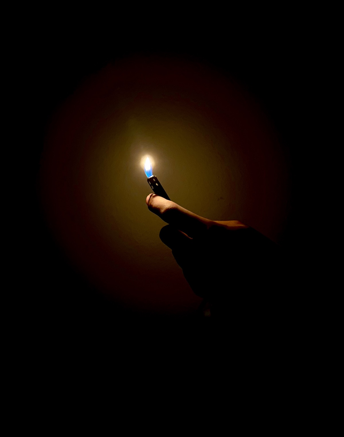 A small flame from a lighter held up in complete darkness